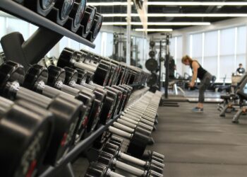 Sala de musculação com piso de borracha preto em placas sob rack de agachamento e anilhas